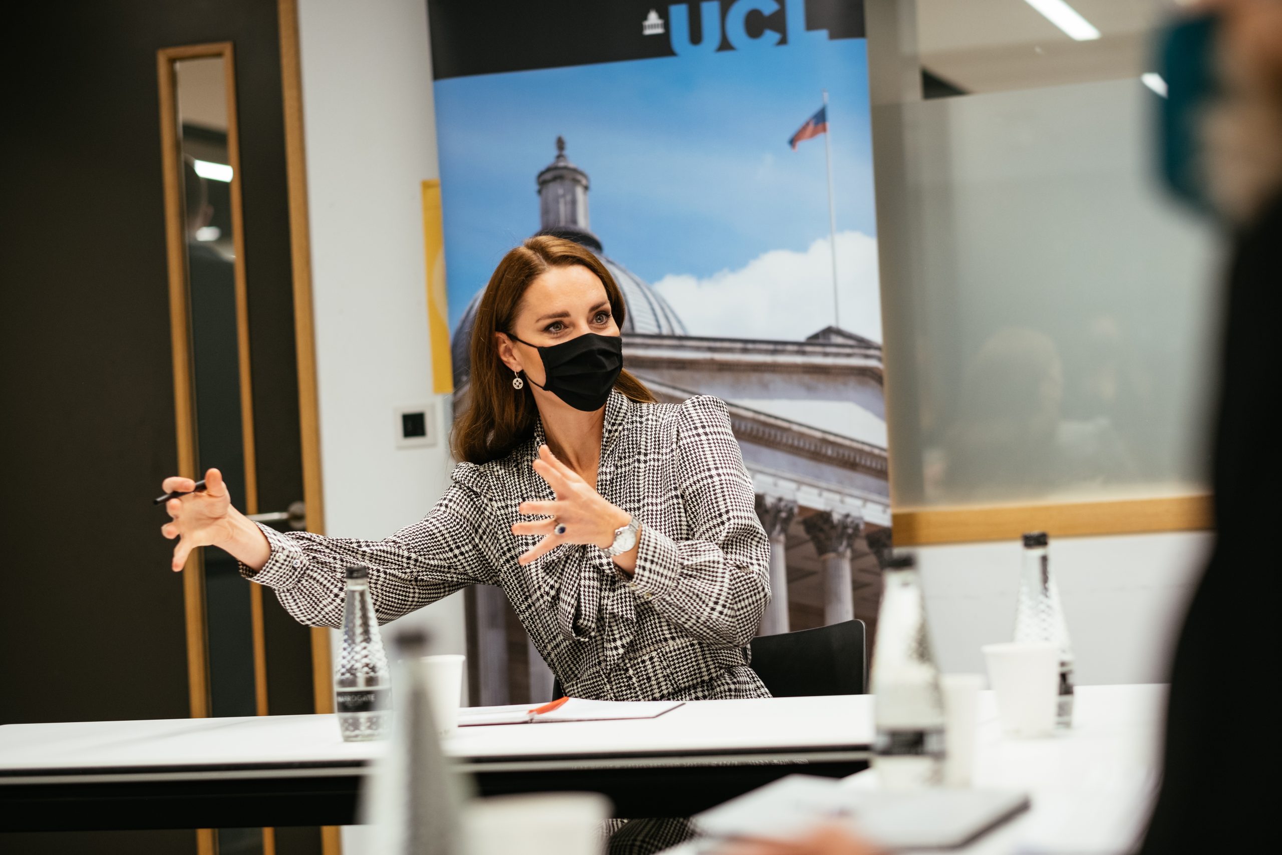 The Duchess of Cambridge explaining something in front of a UCL banner