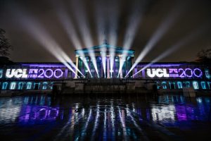 Picture of UCL's main campus with UCL200 lit up on either side of the portico